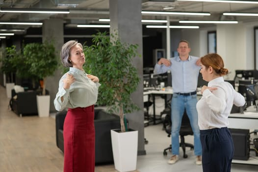 Four office workers warm up during a break. Employees do fitness exercises at the workplace