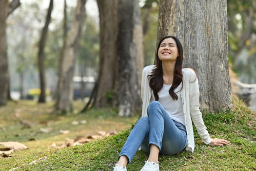 Happy millennial woman relaxing and fresh air in the park. Healthcare lifestyle and wellness concept.