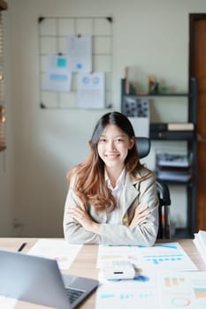 Portrait of a woman business owner showing a happy smiling face as he has successfully invested her business using computers and financial budget documents at work.