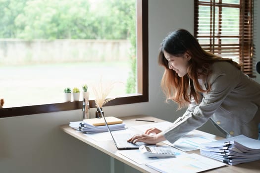 financial, Planning, Marketing and Accounting, portrait of Asian employee checking financial statements using documents and computer laptop at work.