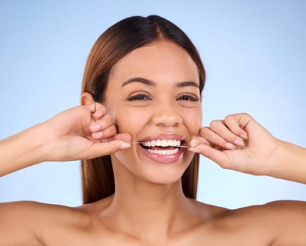 Dental floss, portrait and woman smile with teeth hygiene, healthcare and wellness treatment. Isolated, blue background and studio with a female feeling beauty from a clean mouth with self care.