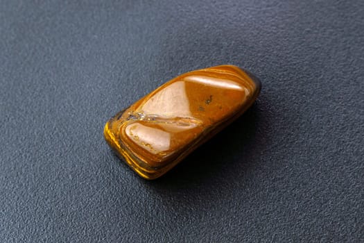 Natural mineral gem stone Tiger eye gemstone on black background close-up.