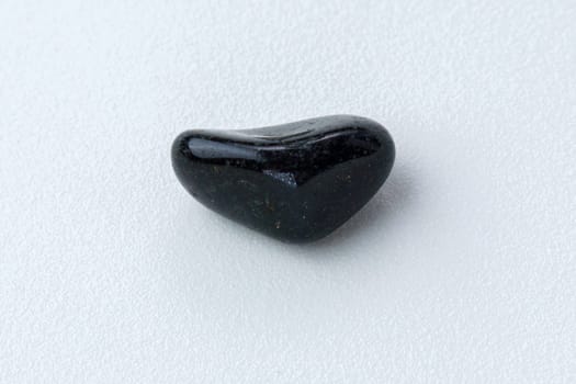 Close up of natural mineral from geological collection tumbled black onyx gem stone, white background