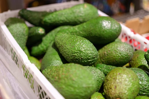 Fresh avocado fruits on the shelves of the hypermarket, selective focus. Goods on a supermarket showcase.