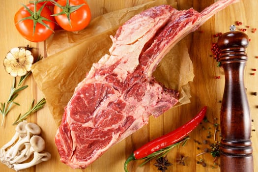 Raw cowboy steak on wooden background, prime rib eye on bone