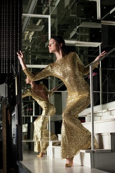 Full length portrait of young woman in fasgion gold dress on stairs
