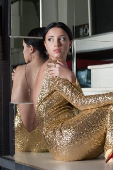 Beautiful young woman portrait in gold dress on stairs