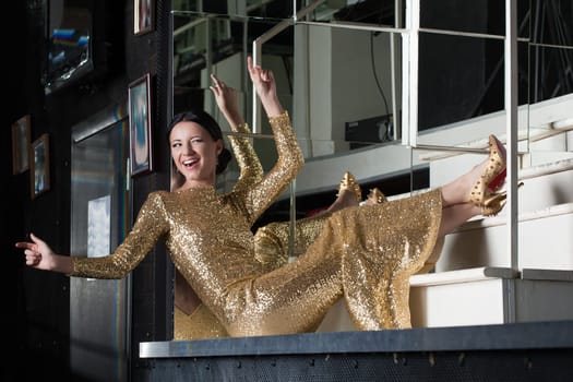 Full length portrait of Amazing woman in gold dress smile on stairs