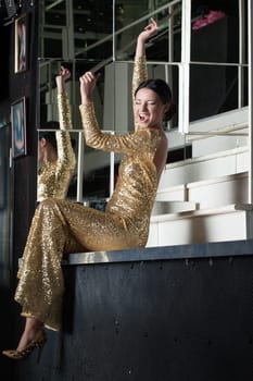 Beauty woman in sexy gold dress have fun on bar table