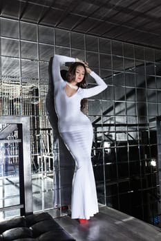 Full length portrait of young woman in beautiful dress in mirrors room of night club
