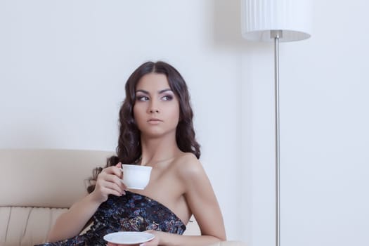 Portrait of brunette woman drinking coffee in living room