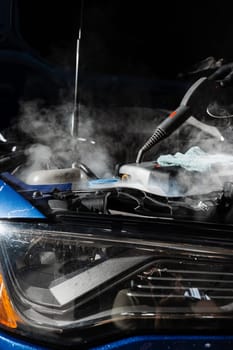 Steaming washing of motor of auto in detailing auto service. Process of steam cleaning car engine from dust and dirt