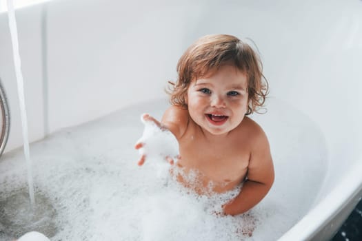 Cute little girl washing in the bat at home. Top view.