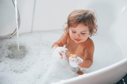 Cute little girl washing in the bat at home. Top view.
