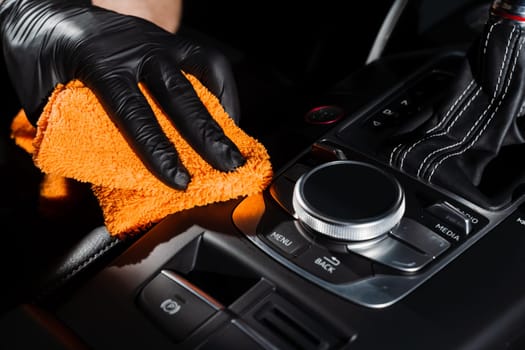 Hand car interior drying of gearbox and dashboard using microfiber in detailing auto service. Cleaner worker dry car interior