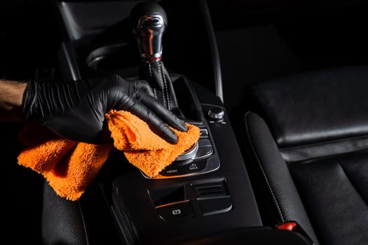 Hand car interior drying of gearbox and dashboard using microfiber in detailing auto service. Cleaner worker dry car interior