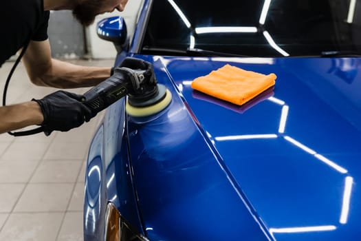 Car polishing with orbital polisher for remove scratches. Worker of detailing auto service making final polishing for car