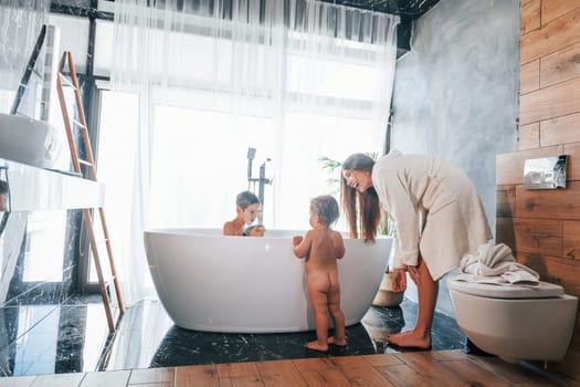 After washing. Young mother helps her son and daughter.