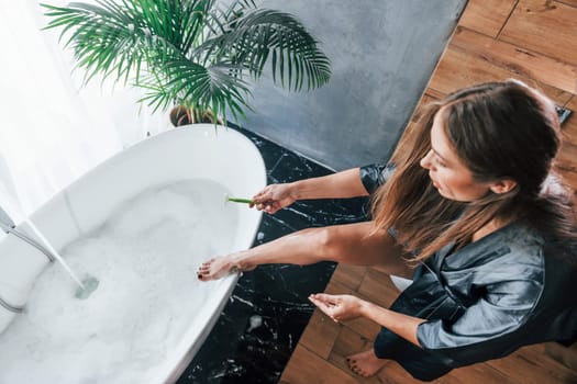 Beautiful young woman have free time at home in the bath. Shaves legs.
