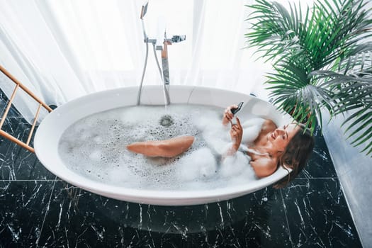 Top view. Beautiful young woman have free time at home in the bath.