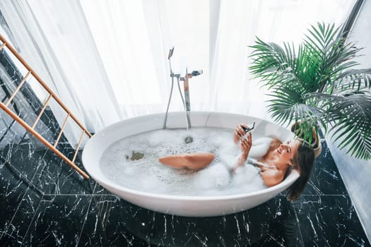 Top view. Beautiful young woman have free time at home in the bath.