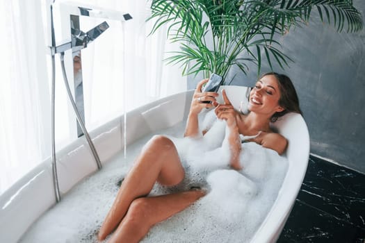 Top view. Beautiful young woman have free time at home in the bath.