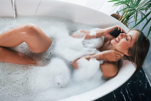 Top view. Beautiful young woman have free time at home in the bath.
