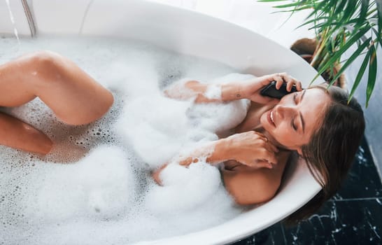 Top view. Beautiful young woman have free time at home in the bath.
