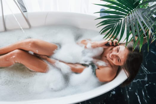 Top view. Beautiful young woman have free time at home in the bath.
