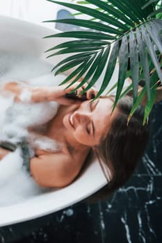 Top view. Beautiful young woman have free time at home in the bath.