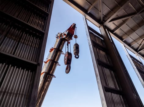 Hoist of crane at the window of industrial plant