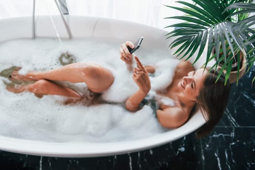Top view. Beautiful young woman have free time at home in the bath.