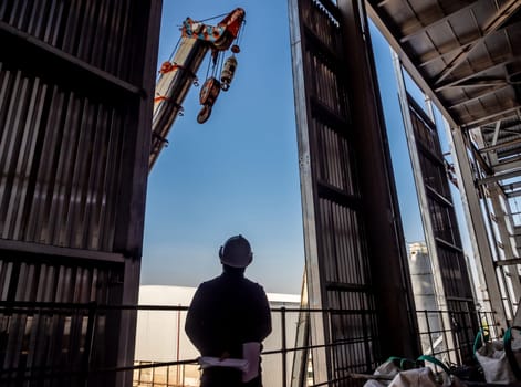 Hoist of crane at the window of industrial plant