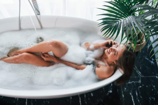 Top view. Beautiful young woman have free time at home in the bath.