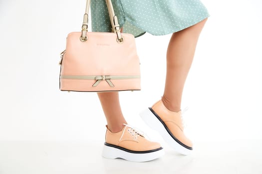 Beautiful sneakers on woman legs in studio on white background. Fashionable shooting of a young girl with beautiful legs