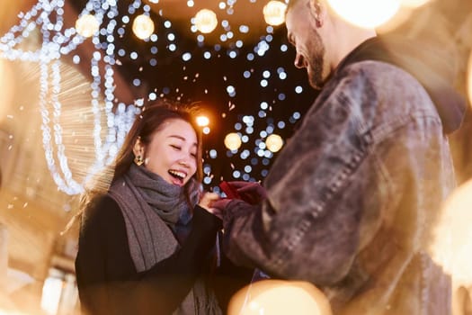 Guy doing proposal. Happy multiracial couple together outdoors in the city celebrating New year.