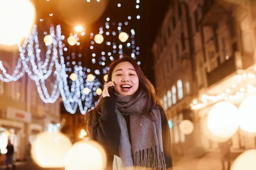 Talks by phone. Cute and happy asian young woman outdoors in the city celebrates New year.