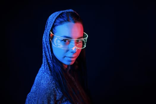 Portrait of young girl that is in eyeglasses in blue neon lighting.