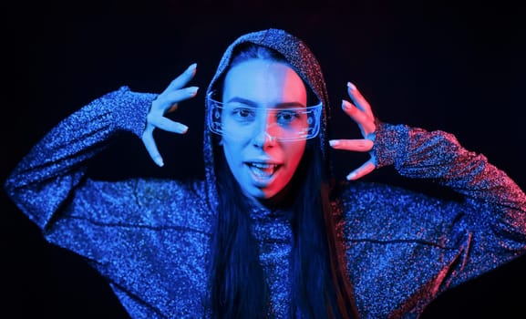 Portrait of young girl that is in eyeglasses in blue neon lighting.