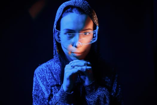 Portrait of young girl that is in eyeglasses in blue neon lighting.