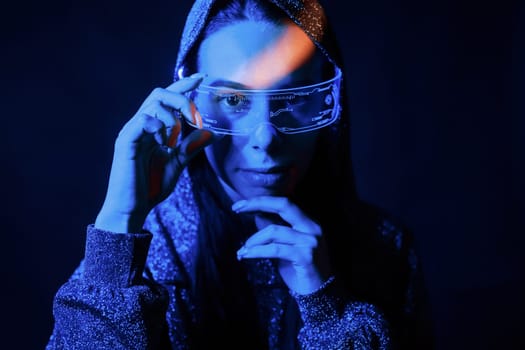 Portrait of young girl that is in eyeglasses in blue neon lighting.