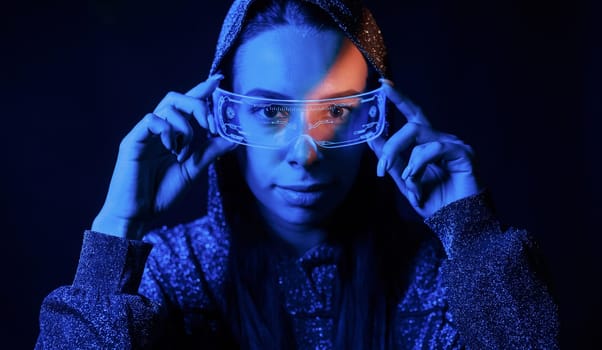 Portrait of young girl that is in eyeglasses in blue neon lighting.