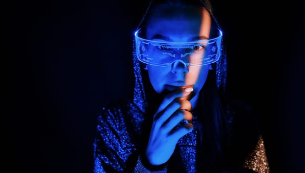Portrait of young girl that is in eyeglasses in blue neon lighting.