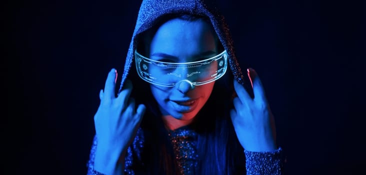 Portrait of young girl that is in eyeglasses in blue neon lighting.