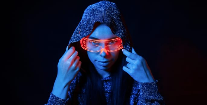 Portrait of young girl that is in eyeglasses in blue neon lighting.