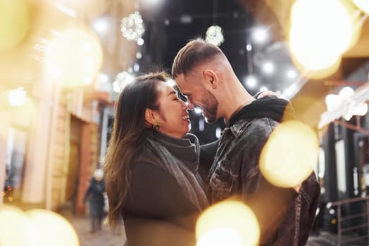 Embracing each other. Happy multiracial couple together outdoors in the city celebrating New year.