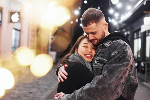 Embracing each other. Happy multiracial couple together outdoors in the city celebrating New year.