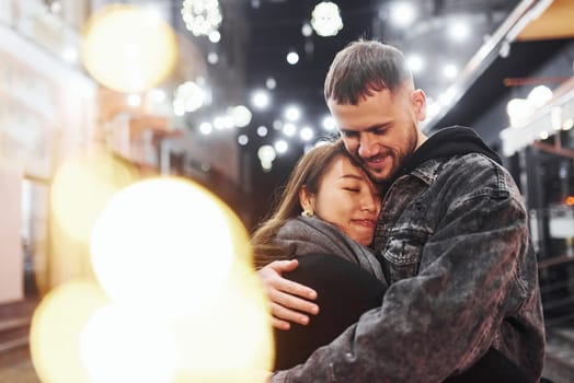 Embracing each other. Happy multiracial couple together outdoors in the city celebrating New year.