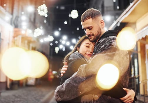 Embracing each other. Happy multiracial couple together outdoors in the city celebrating New year.