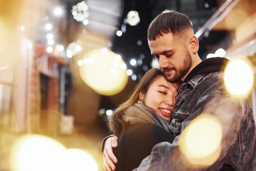Embracing each other. Happy multiracial couple together outdoors in the city celebrating New year.